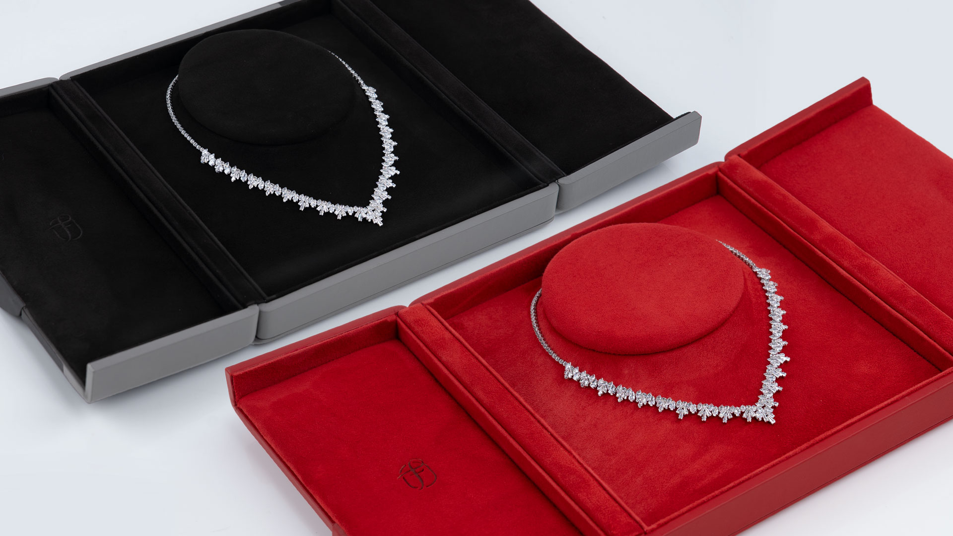Deux écrins Fleur de Luxe ouverts dans les couleurs noir-gris et rouge avec collier de bijoux