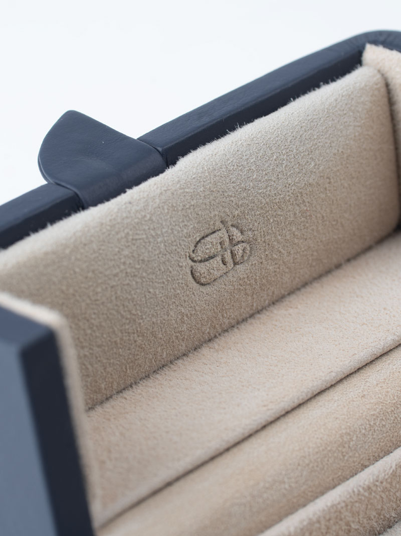 Détail d'un écrin à anneaux en cuir véritable dans les couleurs Indigo-Naturel avec logo en relief à l'intérieur du couvercle à gauche.